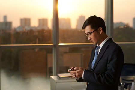 Asian businessman reading messages on his smartphoneの写真素材