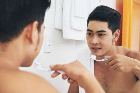 Vietnamese handsome man brushing teeth in bathroomの写真素材