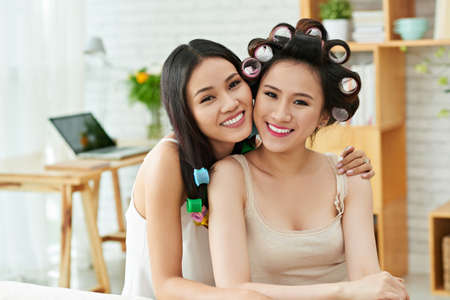 Portrait of two female friends hugging and looking at cameraの写真素材