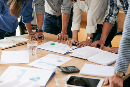 Hands of business team gathered at table with documentsの写真素材