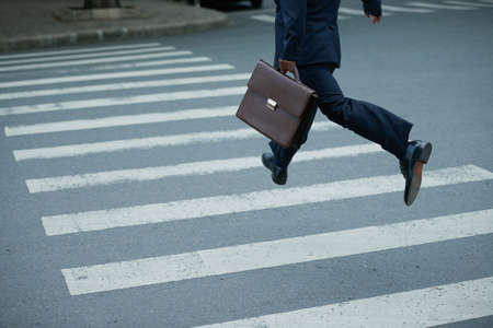 Businessman with briefcase hurry to cross the roadの写真素材