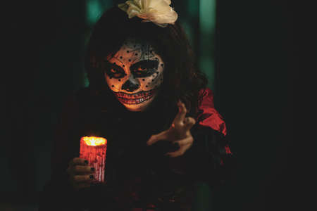 Spooky girl with lighted candle moving towards youの写真素材