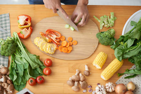 Person cutting ingredients for soup or saladの写真素材