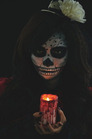Scary girl in Halloween costume holding glowing candle