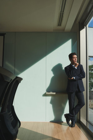Pensive mature entrepreneur standing at office windowの写真素材