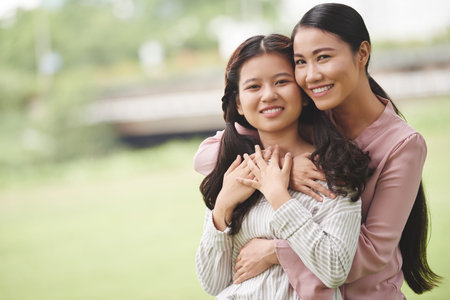 Mother hugging her daughter from behind: happiness of motherhoodの写真素材