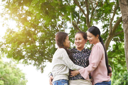Hugging mother, daughter and granddaughter hugging in parkの写真素材