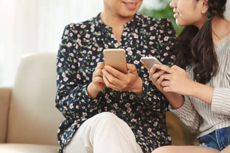 CLose-up image of senior woman and her granddaughter using applications on their smartphonesの写真素材