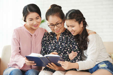 Female generation of Vietnamese family watching photos in albumの写真素材