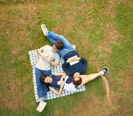 Friends lying on each other when dreaming in parkの写真素材