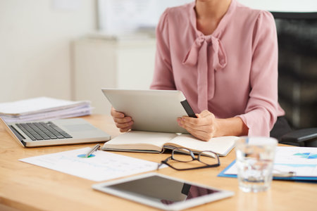 Cropped image of business lady reading data on tablet computer