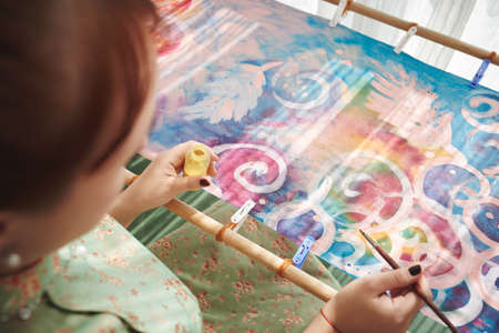 Girl painting ornament on textile, view over the shoulderの写真素材