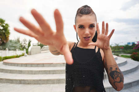 Young woman with tattoos and heavy make-up making gestures with her handsの写真素材