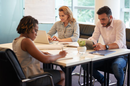 Group of hard-working financial managers preparing annual accounts while sitting in modern boardroom with panoramic windowsの写真素材