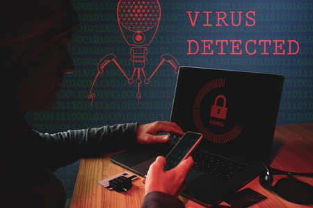 Unrecognizable internet criminal hacking data online, spreading computer virusの写真素材