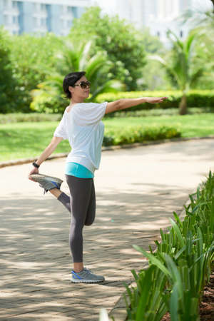 Asian Woman Stretching in Parkの写真素材
