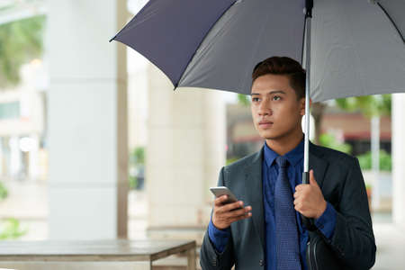 Asian Businessman with Smartphone Outdoorsの写真素材