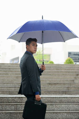 Young Asian Businessman with Umbrella Outdoorsの写真素材