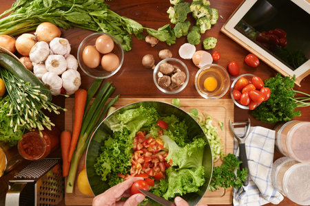 Man preparing meal referring to recipe in tablet PC
