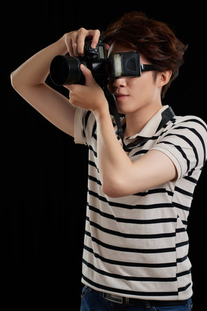 Portrait of young photographer working, isolated on black