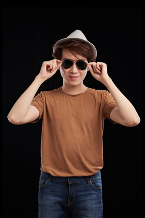 Portrait of cool smiling young man wearing sunglasses, isolated on black