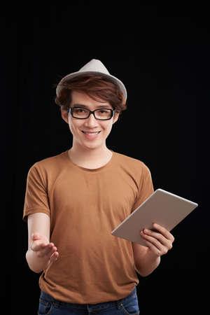Smiling Asian young man with digital tablet asking to you pass a surveyの写真素材