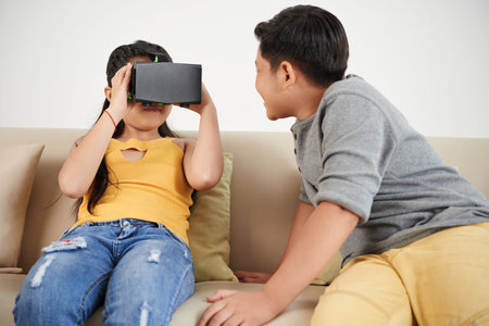 Brother and sister playing games in virtual reality headset