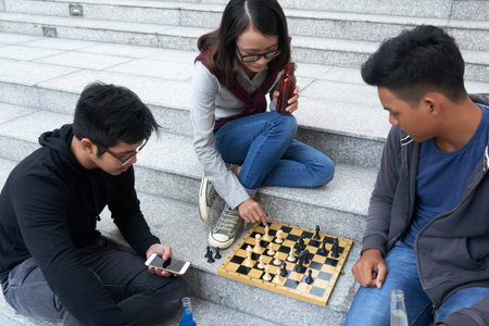 Friends sitting on stairs and playing chess