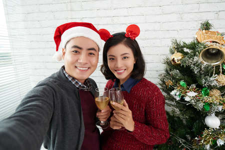 Selfie of two young Asian office workers posing with wine glasses in Christmas timeの写真素材
