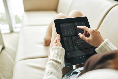 Over shoulder view of unrecognizable young woman sitting on cozy sofa and using digital tablet