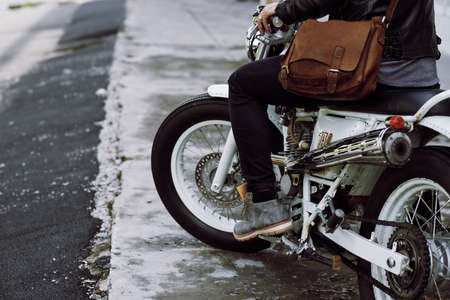 Unrecognizable male biker sitting on vintage motorcycle and pressing gas pedal, ready for searching adventuresの写真素材