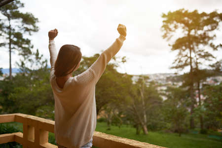 Young woman in sweater enjoying morning on balcony of resort hotelの写真素材