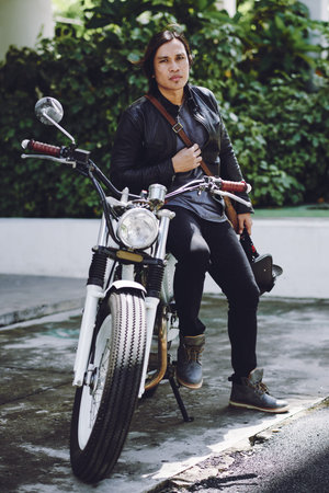 Full length portrait of handsome Asian biker wearing jeans and leather jacket posing for photography...