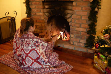 Young couple sitting near fireplace and warming hands on Christmas Eveの写真素材