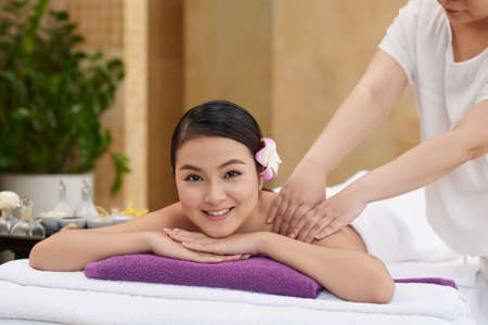 Pretty Asian young woman receiving back massage in spa salonの写真素材