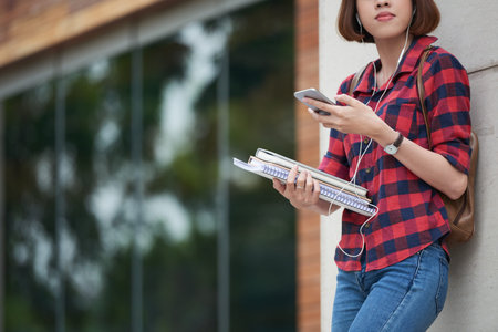 Cropped image of student with textbooks using application on her smartphoneの写真素材