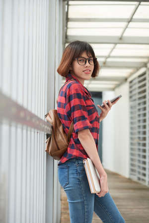 Portrait of female college student with books and smartphoneの写真素材