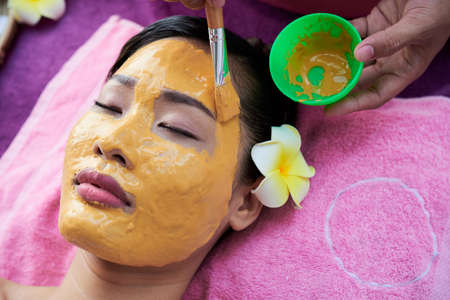 Woman having mask applied on her face in spa salonの写真素材