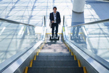Entrepreneur on gyrosceeter standing in end of escalatorの写真素材