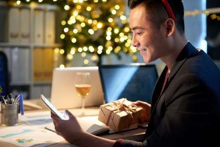 Young businessman congratulating friends with New Year via text messagesの写真素材