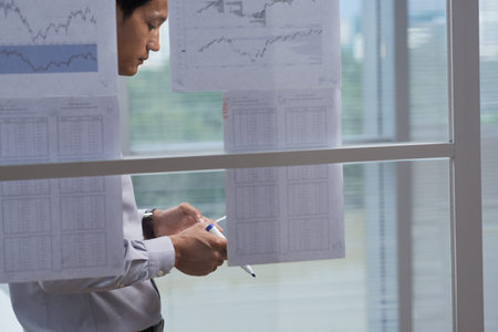 Businessman comparing information on tablet computer with data on hanging reportsの写真素材