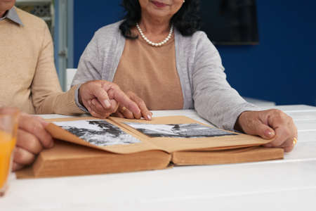 Close-up image of senior couple discussing black and white photos in albumの写真素材