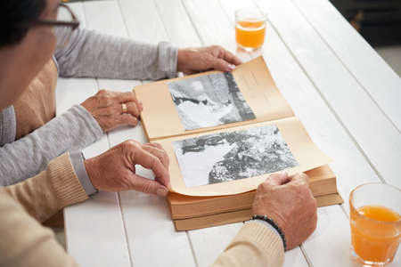 Hands of senior couple looking at old photosの写真素材