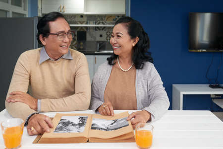 Cheerful senior couple looking at old photos in albumの写真素材