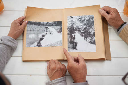 Hands of senior couple looking at their wedding photos, view from aboveの写真素材
