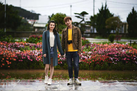 Happy young couple standing in the street and holding handsの写真素材