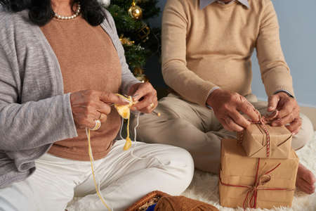 Grandfather packing presents and grandmother knitting for Christmasの写真素材
