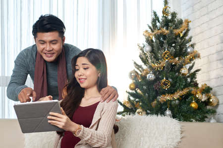 Young woman showing the item on sale in online store to her husbandの写真素材