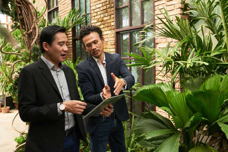 Vietnamese businessman showing project on tablet computer to his coworkerの写真素材