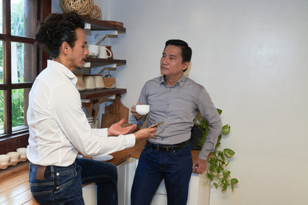 Adult friends drinking tea and talking in kitchenの写真素材